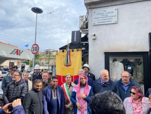 Vertreter der kommunalen Politik, der Region, der Religions- und Glaubensgemeinschaften stehen unter dem neuen Straßenschild